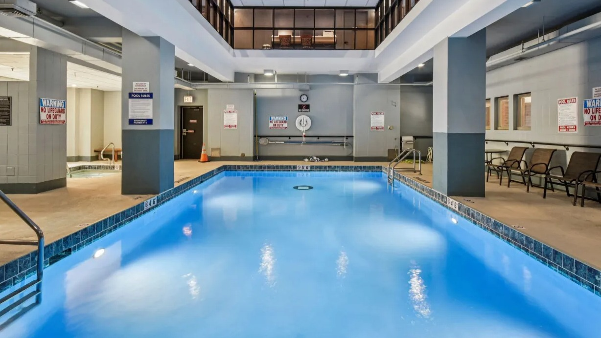 Spacious indoor swimming pool at 100 W Chestnut in Chicago with lap lanes, deck seating, and bright overhead lighting for year-round swimming