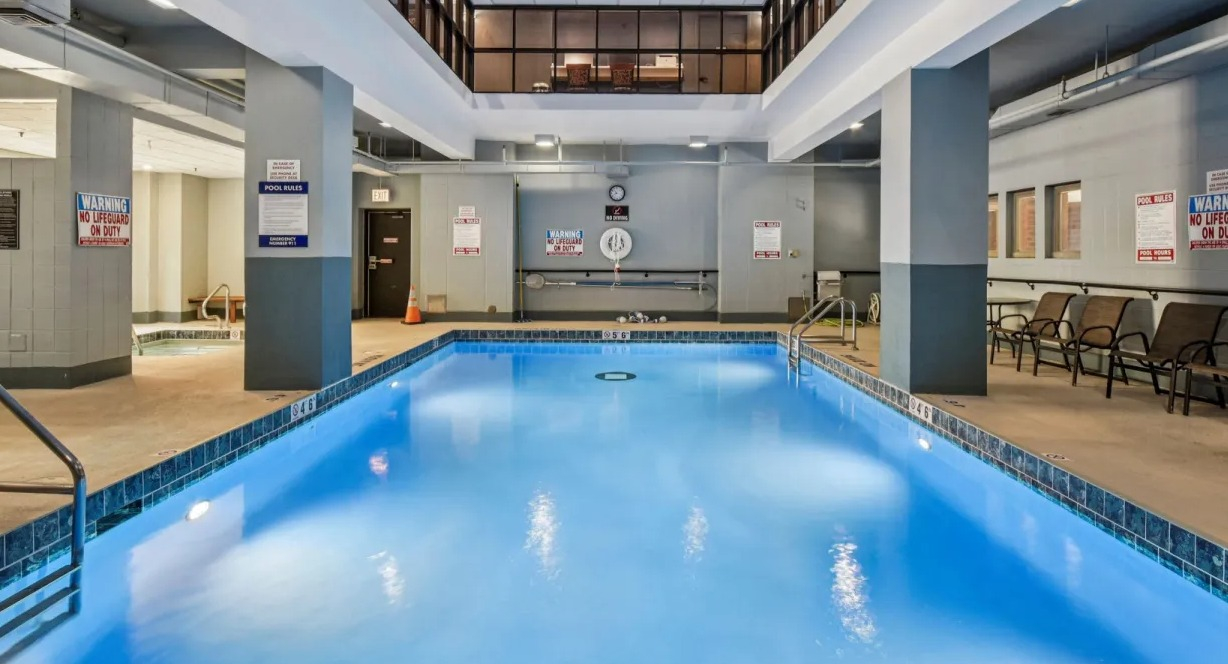 Spacious indoor swimming pool at 100 W Chestnut in Chicago with lap lanes, deck seating, and bright overhead lighting for year-round swimming