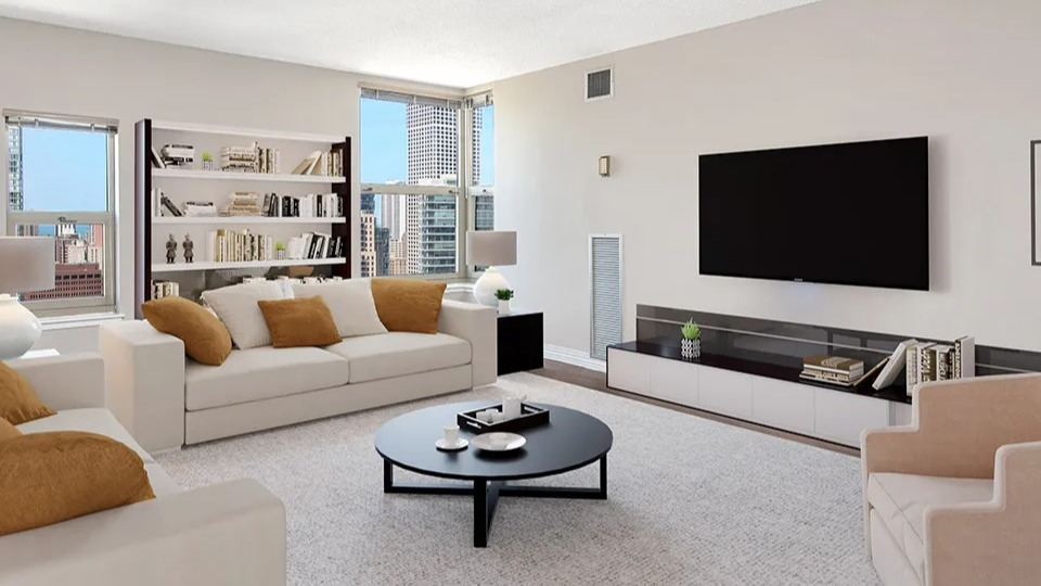 Large living room at 100 W Chestnut in Chicago with two sofas, accent chairs, built-in shelving, and big windows creating an airy, open layout