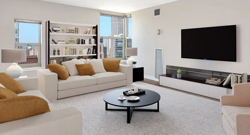 Large living room at 100 W Chestnut in Chicago with two sofas, accent chairs, built-in shelving, and big windows creating an airy, open layout