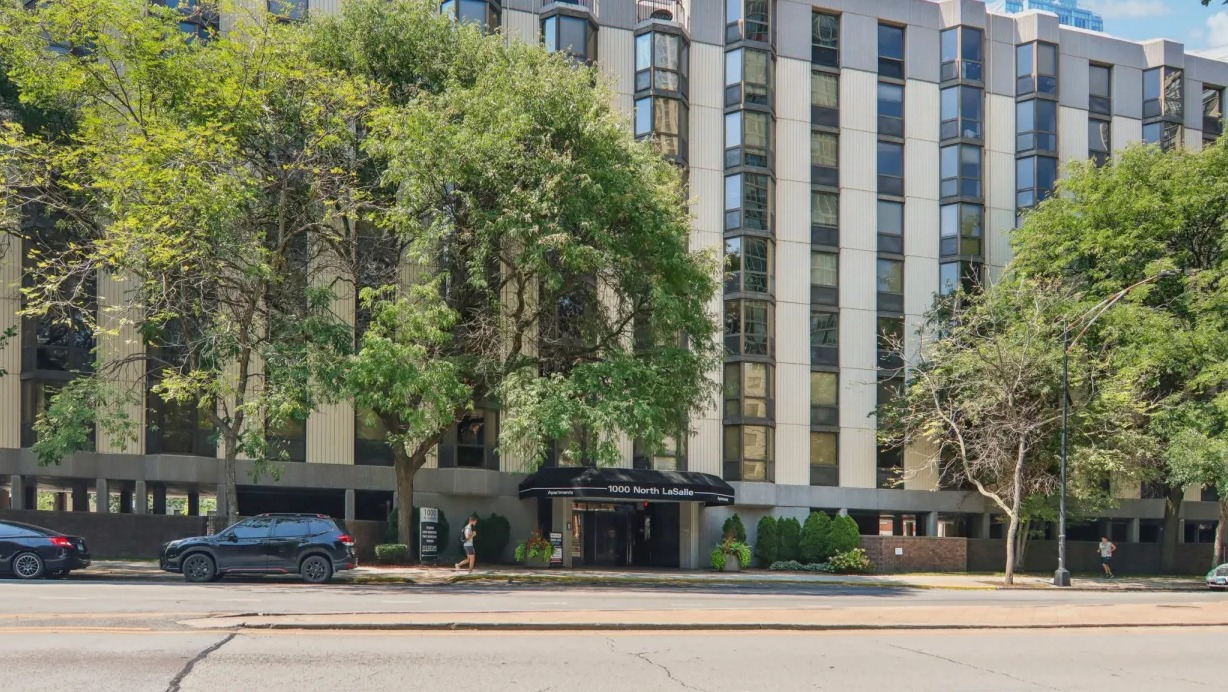 Exterior view of 1000 N LaSalle apartments in Chicago with bay windows, tree-lined street, and central entrance in Gold Coast neighborhood