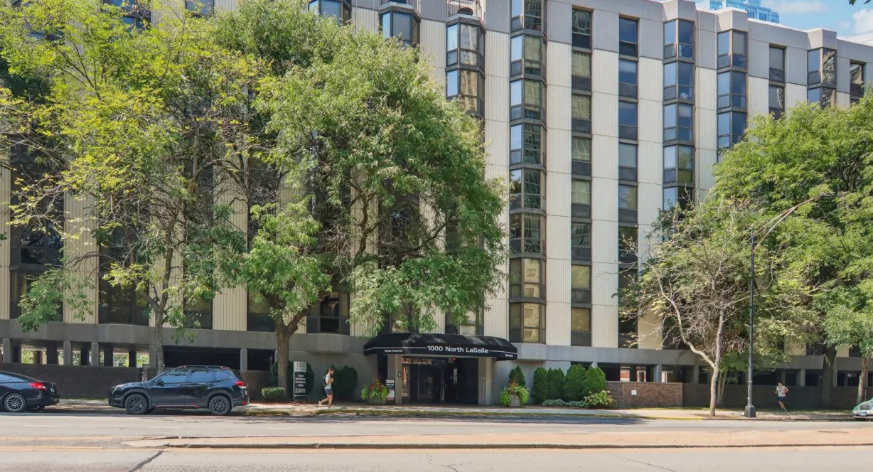 Exterior view of 1000 N LaSalle apartments in Chicago with bay windows, tree-lined street, and central entrance in Gold Coast neighborhood