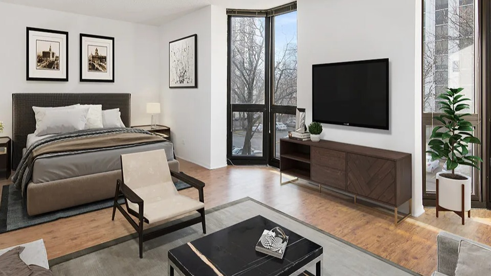 Bright studio at 1000 N LaSalle in Chicago with queen bed, TV, sectional sofa, wood floors, and floor-to-ceiling windows with street views