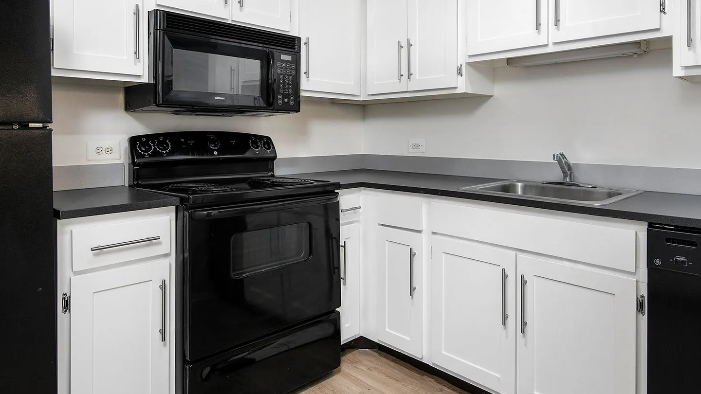 Classic U-shaped kitchen featuring white shaker cabinets, black appliances, and gray countertops in an efficient layout at 1000 N LaSalle apartments, Chicago