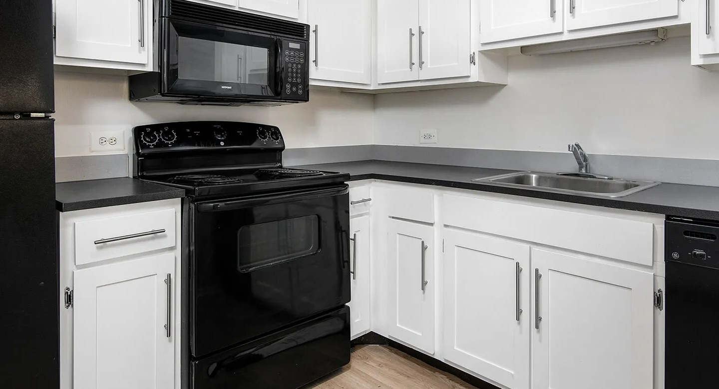 Classic U-shaped kitchen featuring white shaker cabinets, black appliances, and gray countertops in an efficient layout at 1000 N LaSalle apartments, Chicago