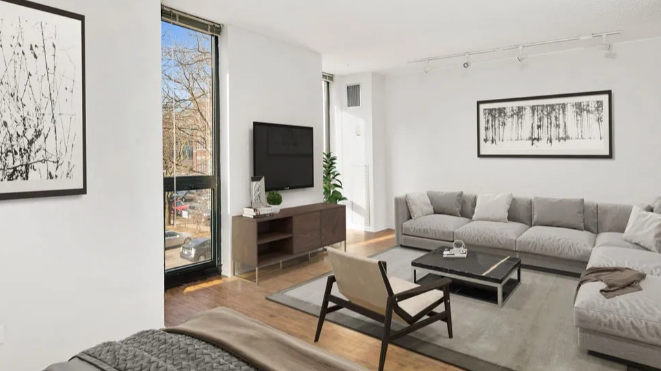 Cozy living room at 1000 N LaSalle in Chicago with sectional sofa, wall-mounted TV, large windows, and modern black-and-white artwork