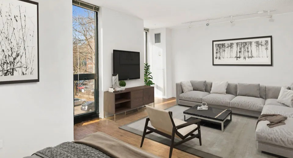 Cozy living room at 1000 N LaSalle in Chicago with sectional sofa, wall-mounted TV, large windows, and modern black-and-white artwork