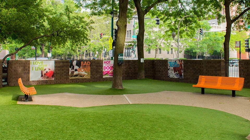 Pet-friendly dog park at 1000 N LaSalle in Chicago with fenced area, benches, artificial turf, and shaded trees in a private courtyard