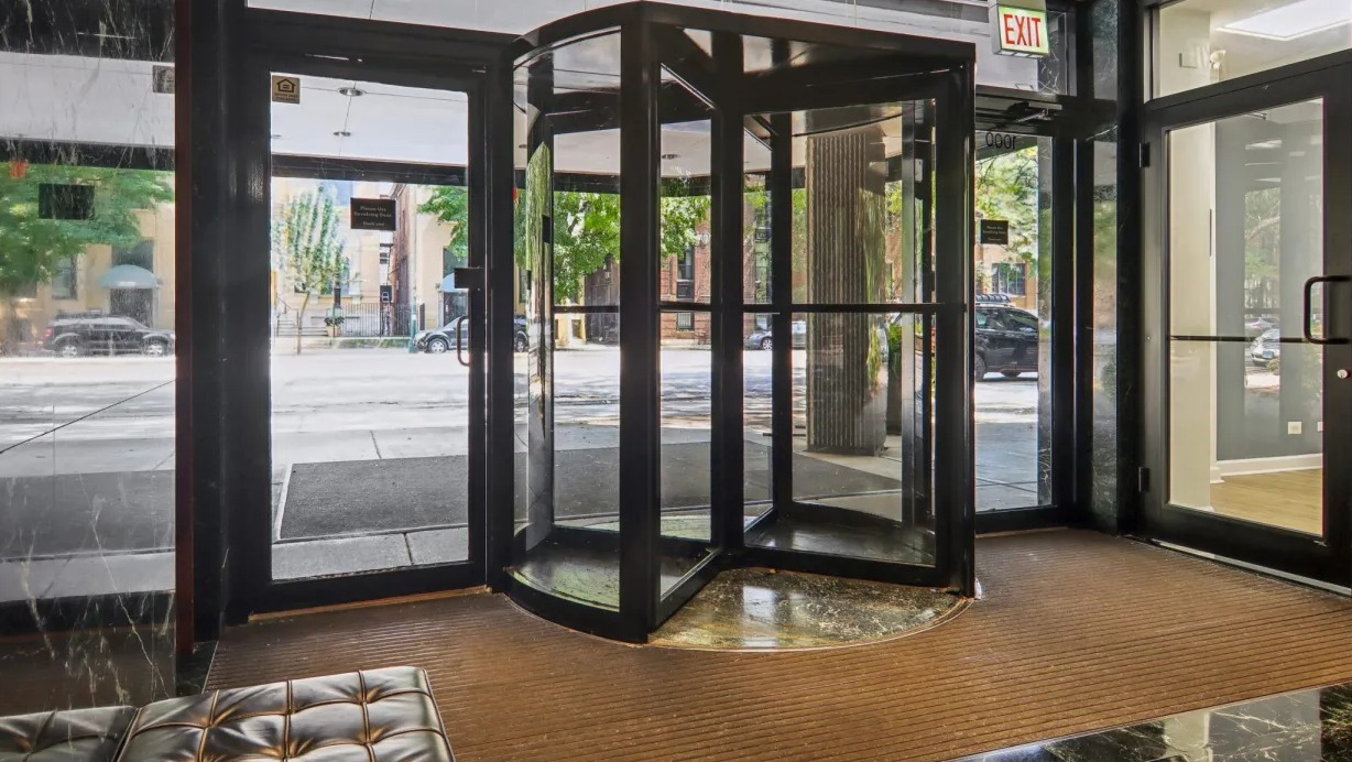 Lobby entrance at 1000 N LaSalle in Chicago featuring revolving glass door, polished black marble walls, and seating area