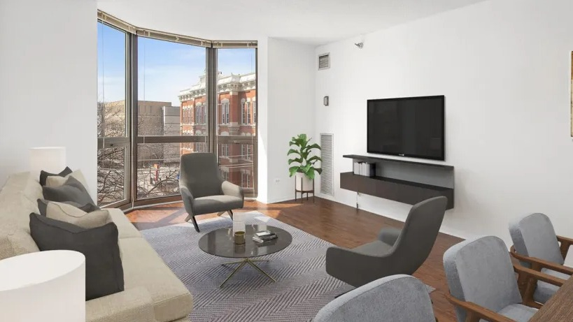 Contemporary living area with bay window, wall-mounted TV, sofa, accent chairs, and adjacent dining space at 1000 N LaSalle apartments in Chicago