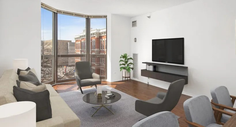 Contemporary living area with bay window, wall-mounted TV, sofa, accent chairs, and adjacent dining space at 1000 N LaSalle apartments in Chicago