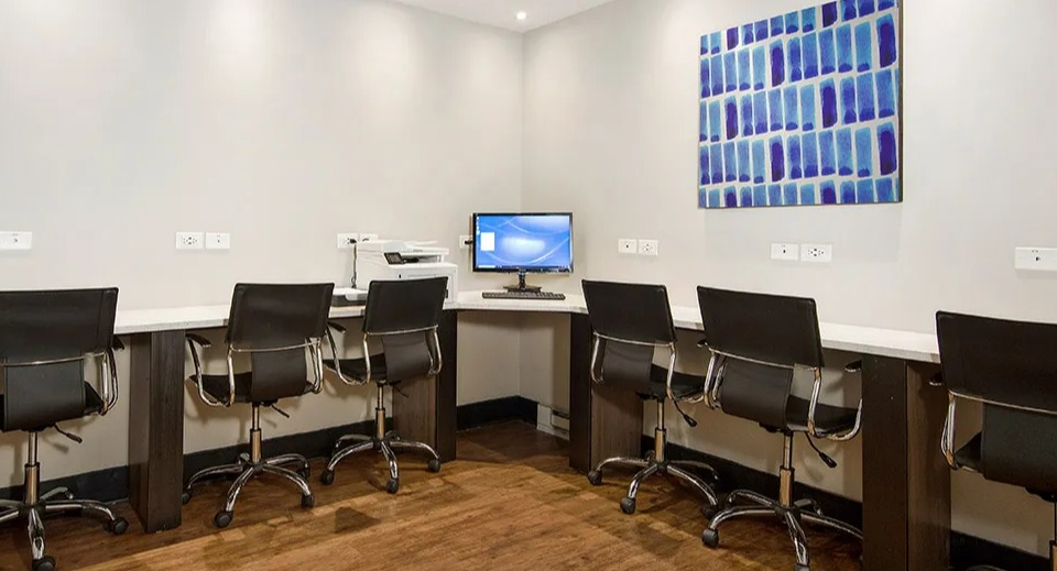 Resident business center featuring long counters, task chairs on casters, ample outlets, and a desktop station for printing at 1000 N LaSalle in Chicago
