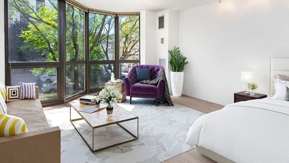Large studio layout with bed, seating area, and expansive bay windows that fill the open space with light at 1000 N LaSalle apartments in Chicago