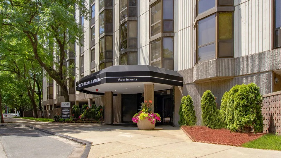 Welcoming entrance at 1000 N LaSalle in Chicago with black canopy, planters of flowers, and tree-lined sidewalk in the Gold Coast neighborhood