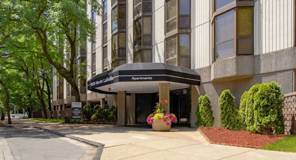 Welcoming entrance at 1000 N LaSalle in Chicago with black canopy, planters of flowers, and tree-lined sidewalk in the Gold Coast neighborhood