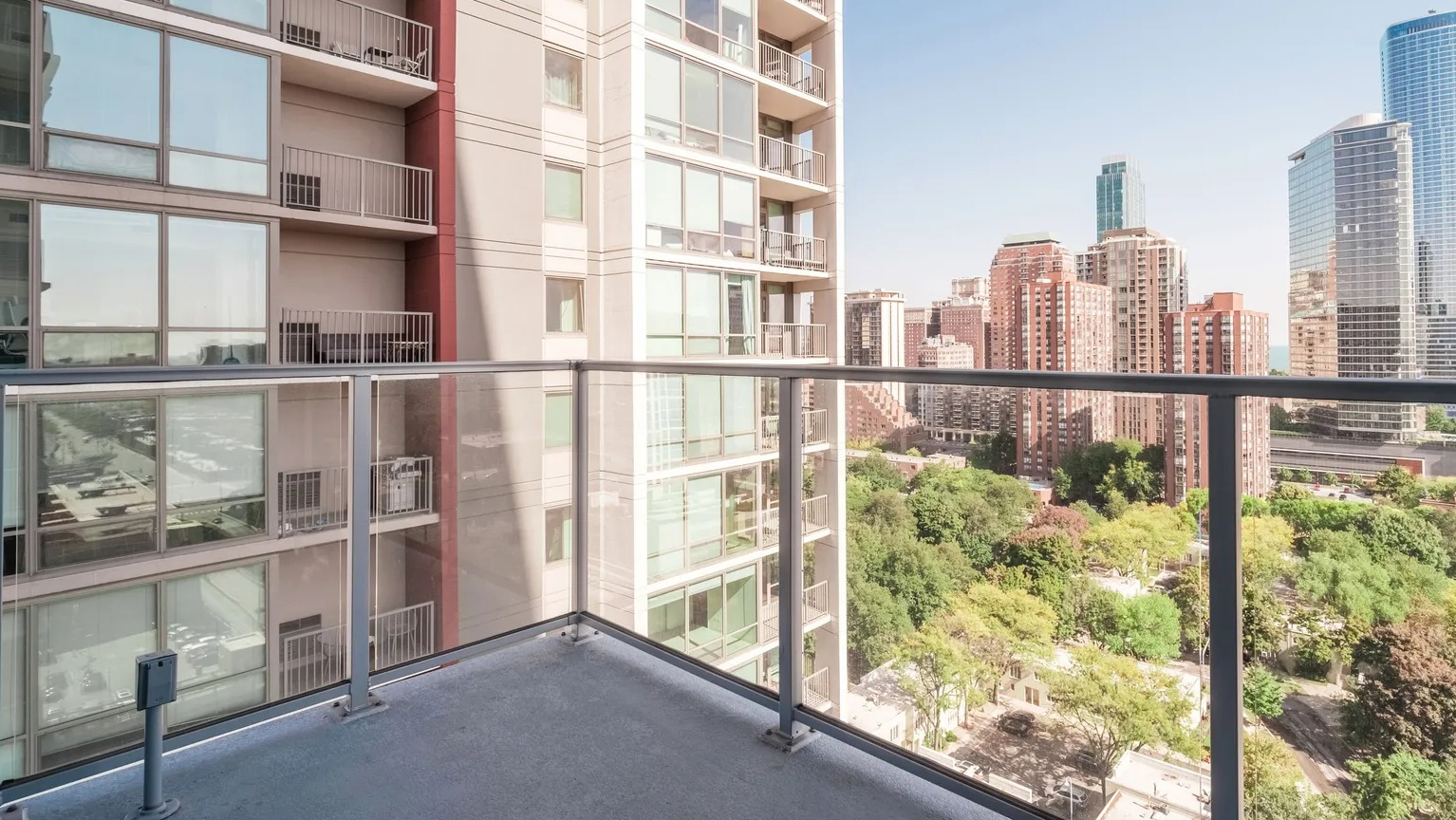Private balcony with glass railing overlooking Chicago skyline and Lake Michigan, offering outdoor living at 1000 South Clark apartments
