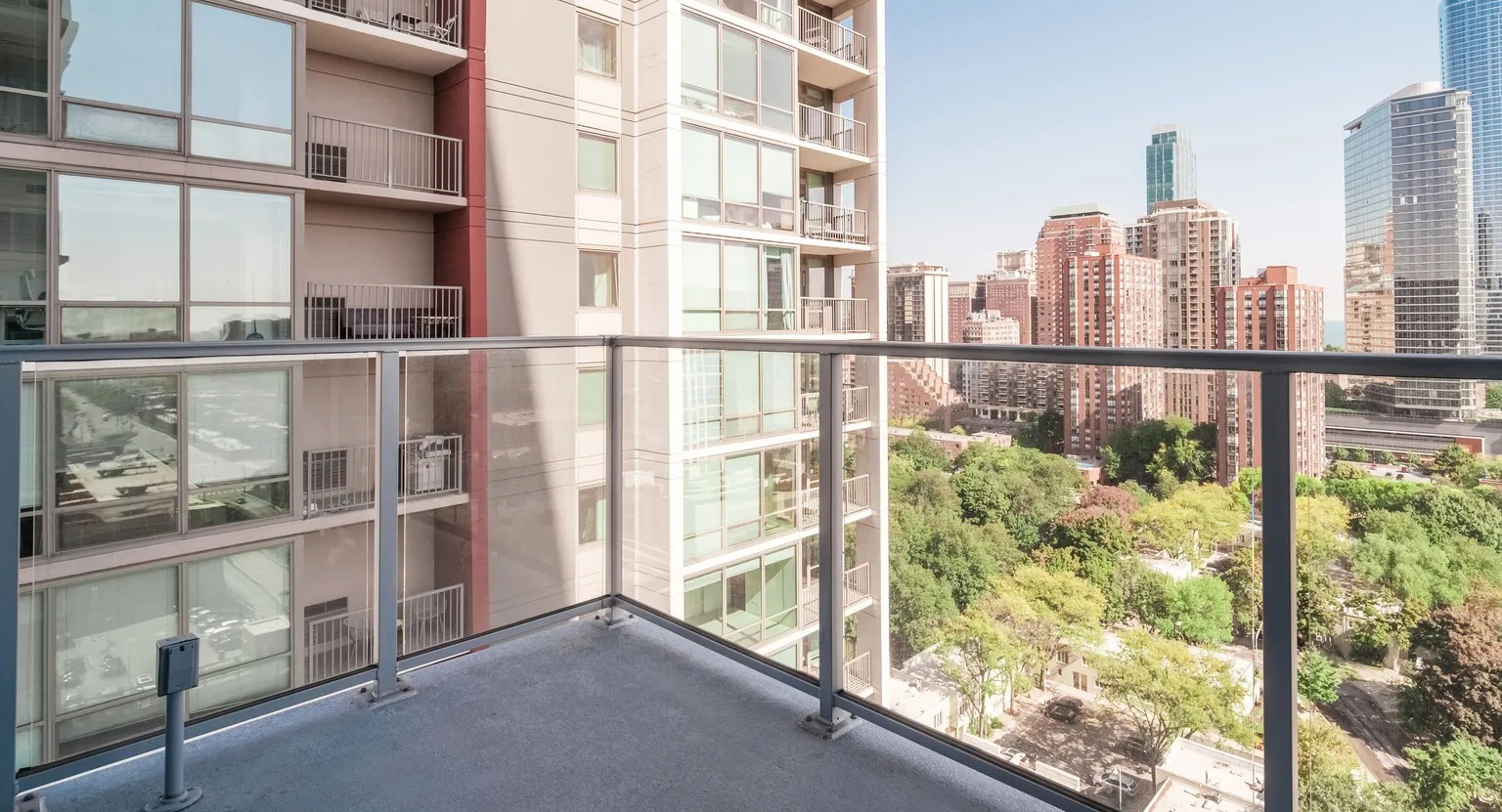 Private balcony with glass railing overlooking Chicago skyline and Lake Michigan, offering outdoor living at 1000 South Clark apartments