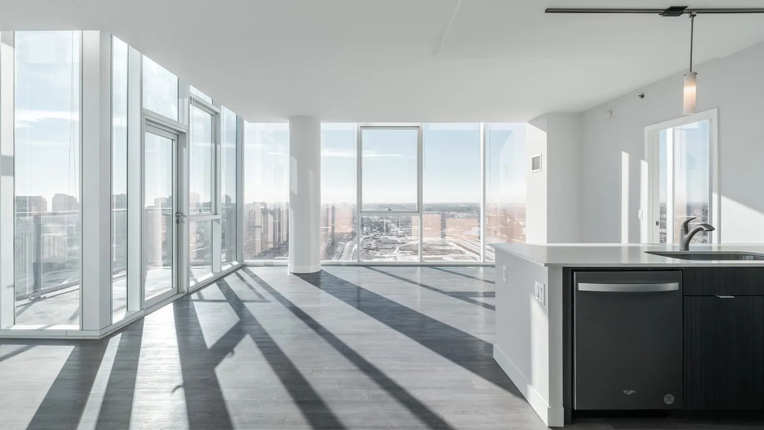 Corner living room surrounded by floor-to-ceiling windows with expansive city views and natural light at 1000 South Clark apartments in Chicago