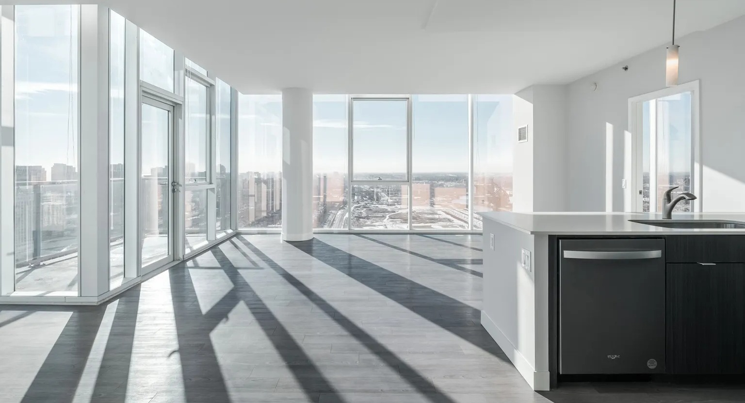 Corner living room surrounded by floor-to-ceiling windows with expansive city views and natural light at 1000 South Clark apartments in Chicago