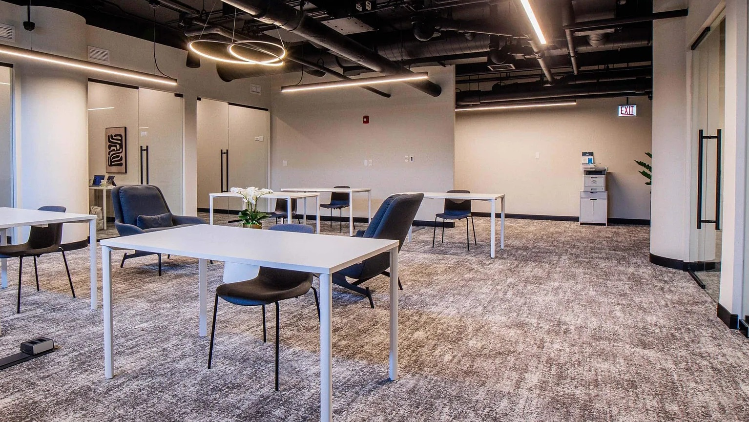 Modern coworking lounge with individual desks, comfy chairs, glass meeting rooms, and contemporary lighting at 1000 South Clark apartments in Chicago