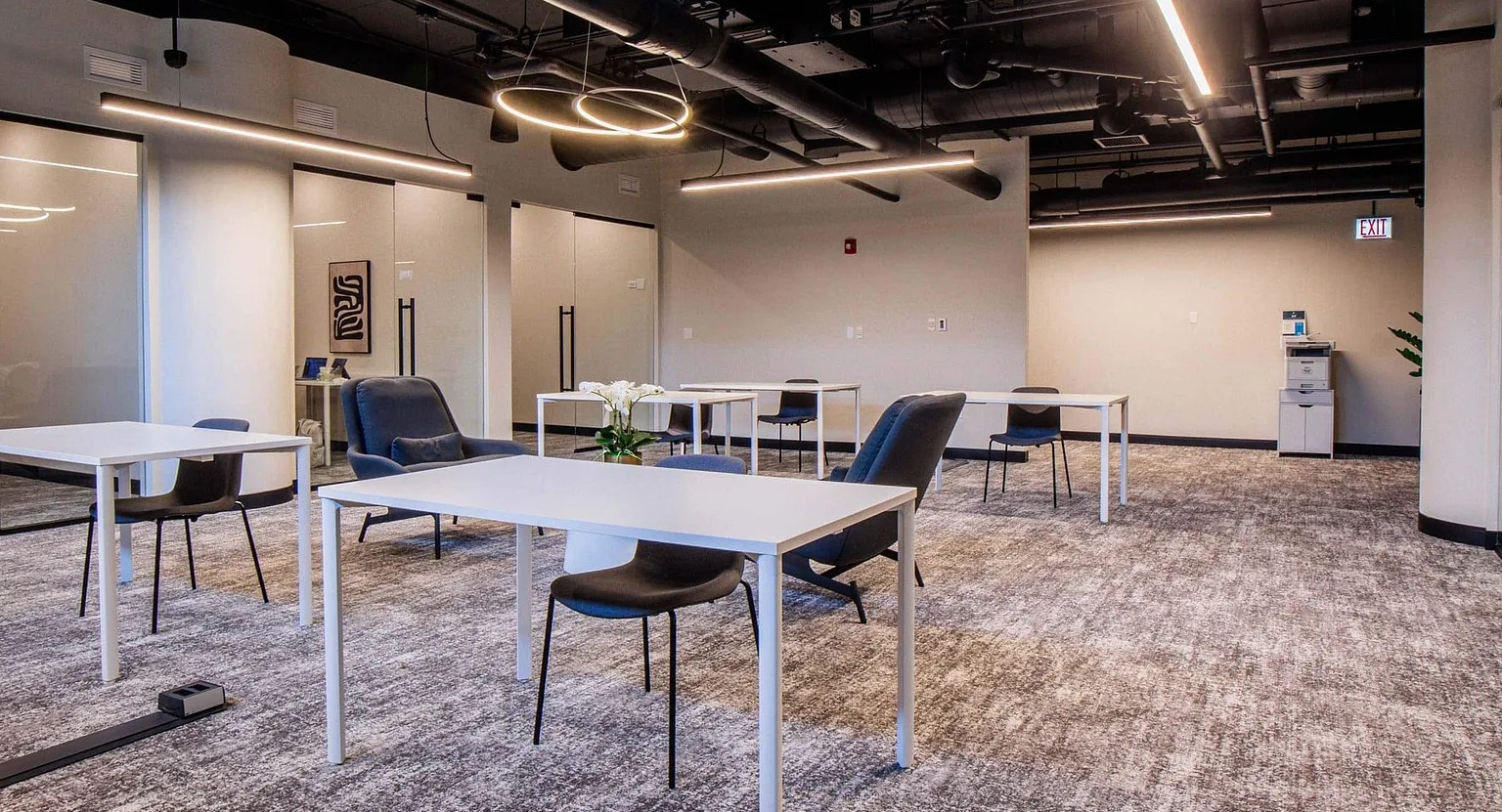 Modern coworking lounge with individual desks, comfy chairs, glass meeting rooms, and contemporary lighting at 1000 South Clark apartments in Chicago
