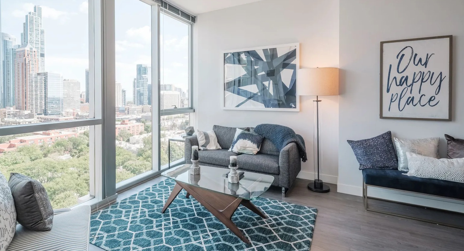 Cozy living room with modern furniture, artwork, and floor-to-ceiling windows overlooking Chicago skyline at 1000 South Clark apartments
