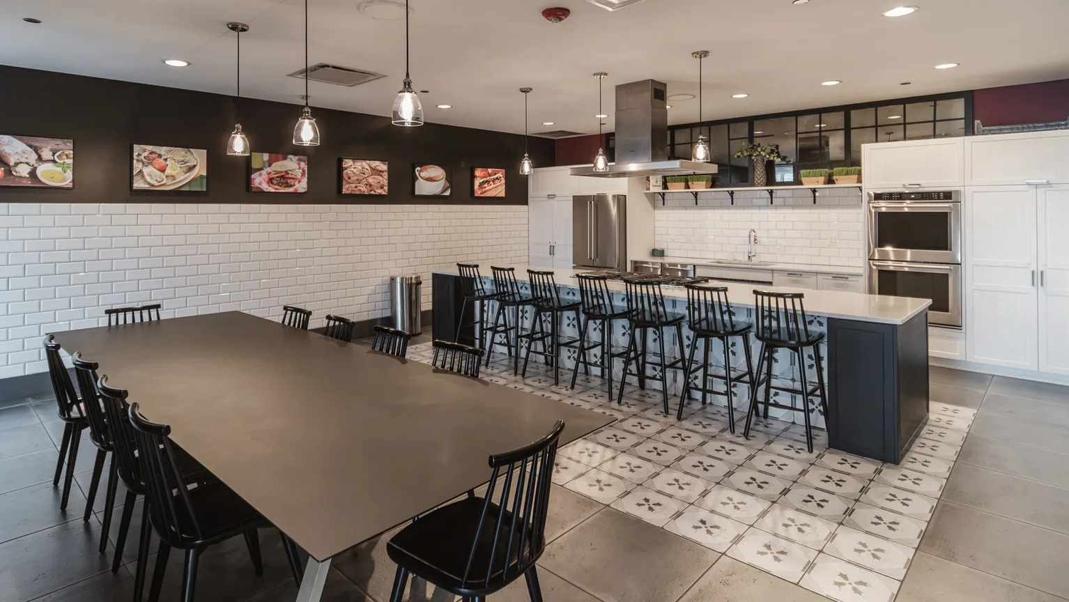 Community demonstration kitchen with long island seating, pendant lights, and adjacent dining table at 1000 South Clark apartments in Chicago