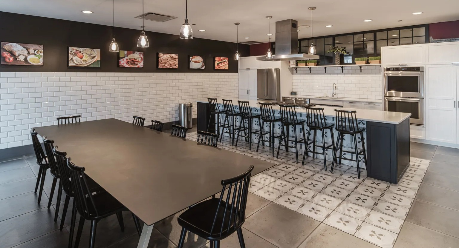 Community demonstration kitchen with long island seating, pendant lights, and adjacent dining table at 1000 South Clark apartments in Chicago