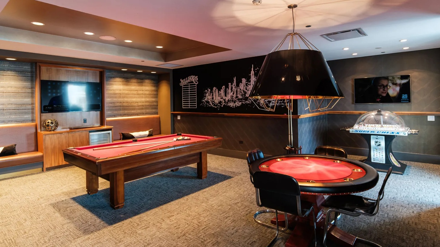 Resident game room featuring pool table, poker table, and lounge seating with TV at 1000 South Clark apartments in Chicago