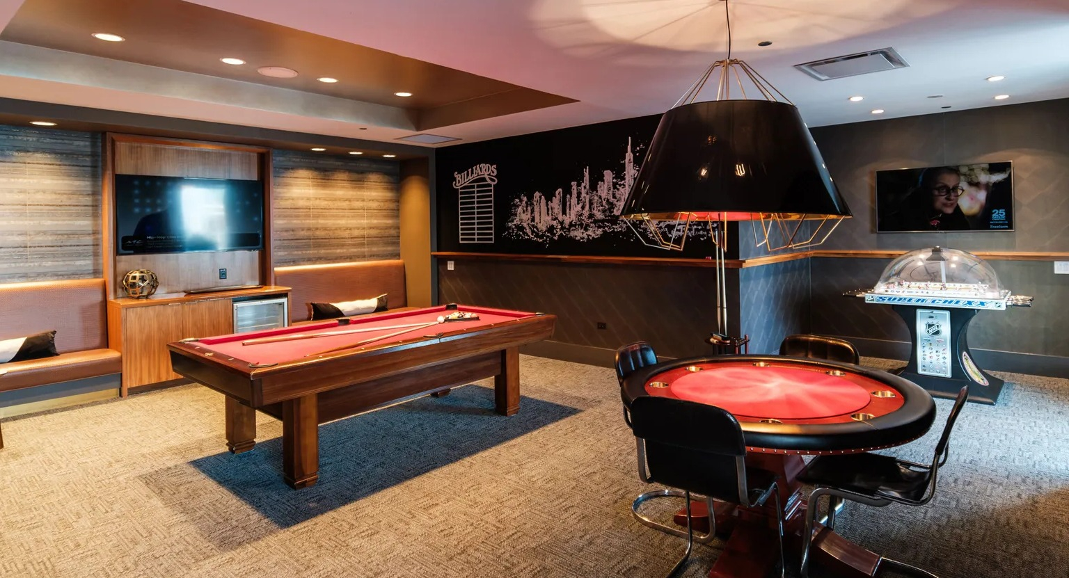 Resident game room featuring pool table, poker table, and lounge seating with TV at 1000 South Clark apartments in Chicago