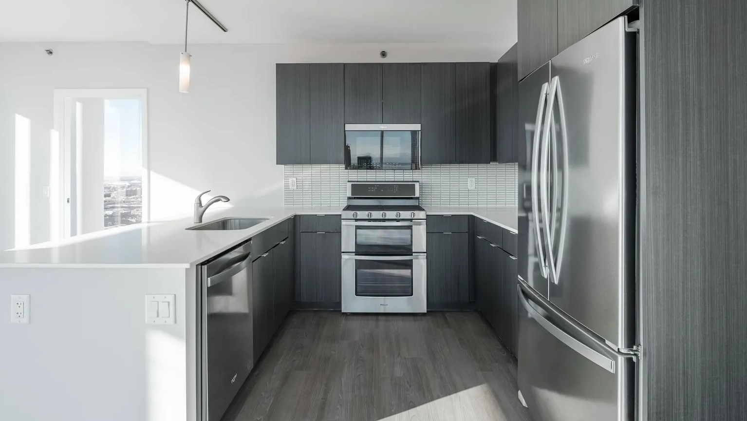 U-shaped kitchen with large island, dark cabinetry, stainless appliances, and bright natural light at 1000 South Clark apartments in Chicago