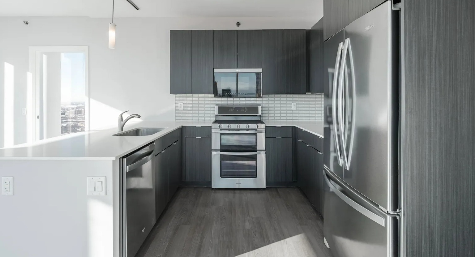 U-shaped kitchen with large island, dark cabinetry, stainless appliances, and bright natural light at 1000 South Clark apartments in Chicago