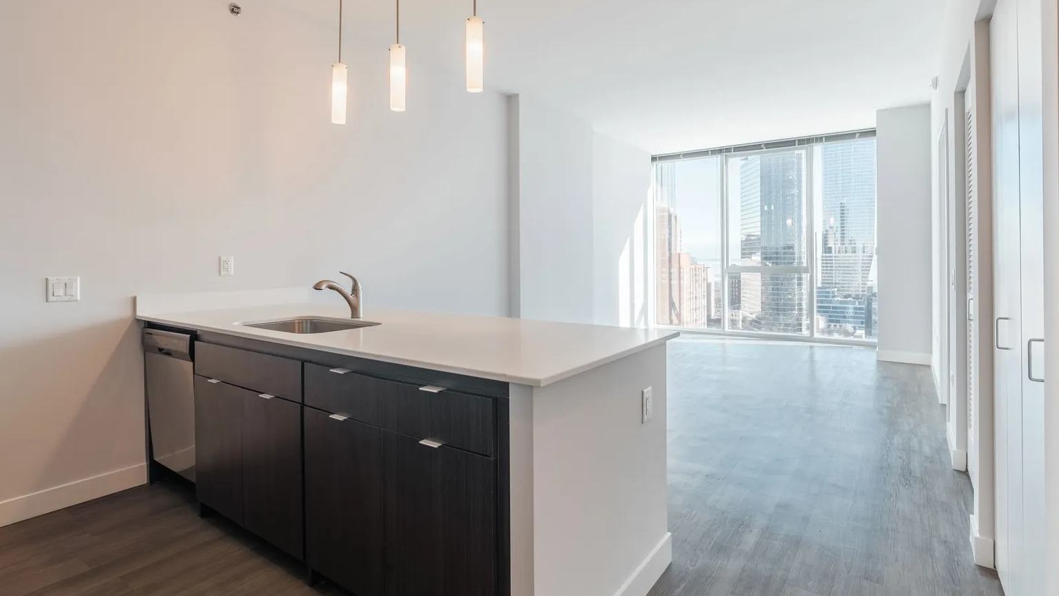 Sleek modern kitchen with dark cabinetry, pendant lighting, and open layout leading to floor-to-ceiling windows at 1000 South Clark in Chicago
