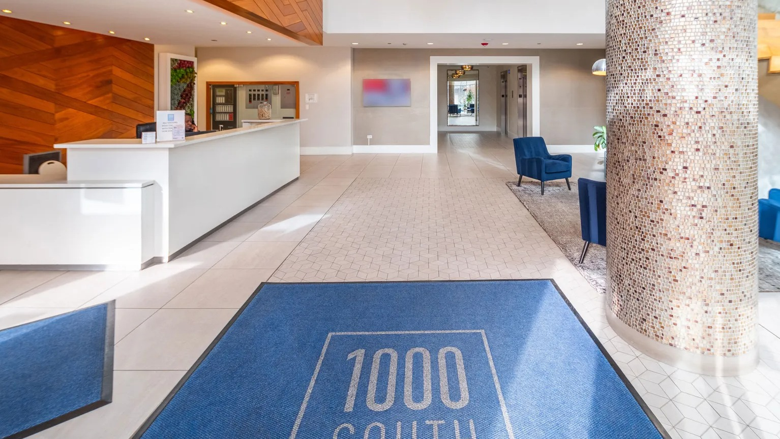 Modern lobby with wood accent walls, chandelier, front desk, and stylish seating at 1000 South Clark apartments in Chicago