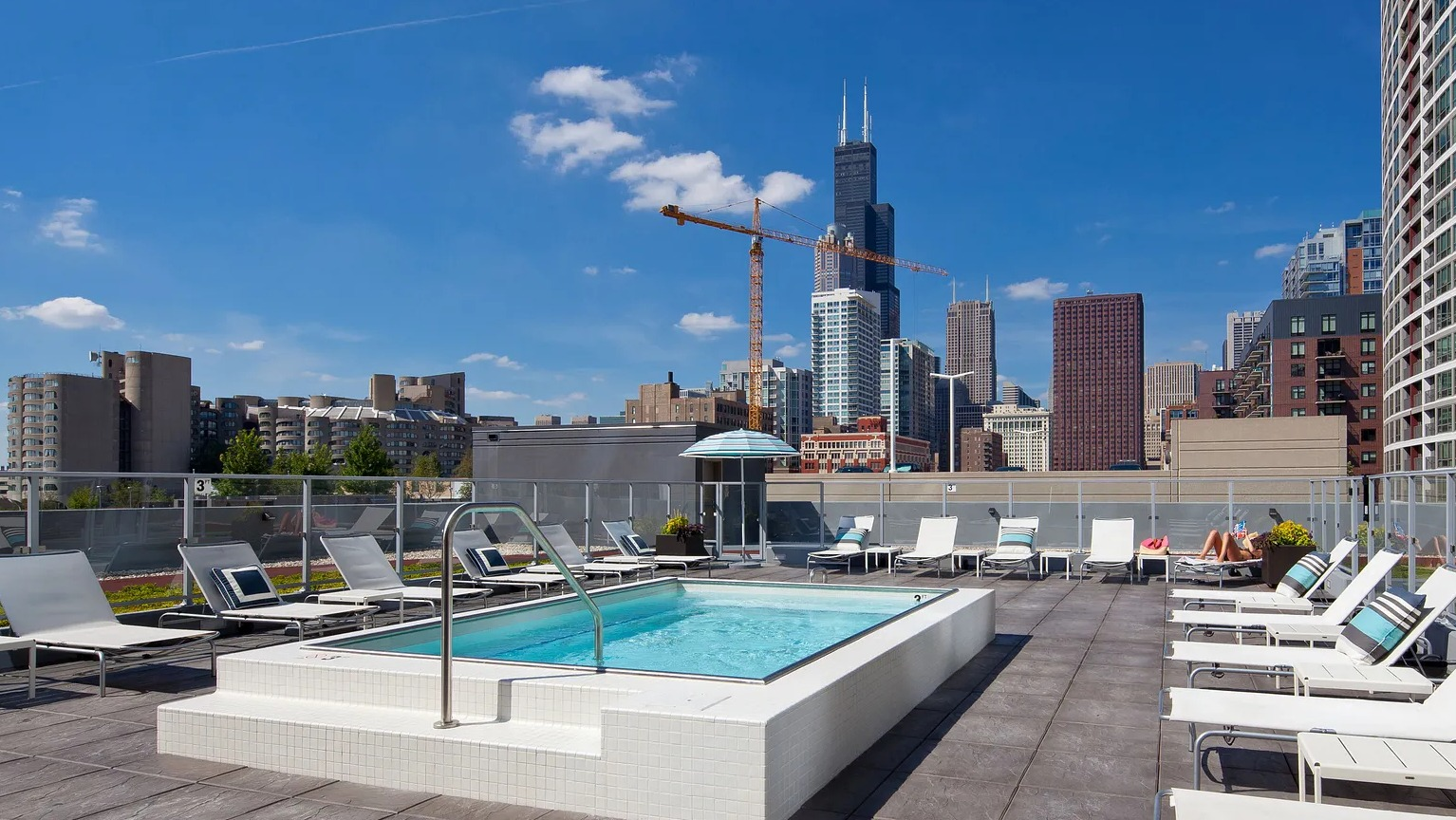 Rooftop spa and sundeck with lounge chairs, glass railings, and skyline views including Willis Tower at 1000 South Clark apartments in Chicago
