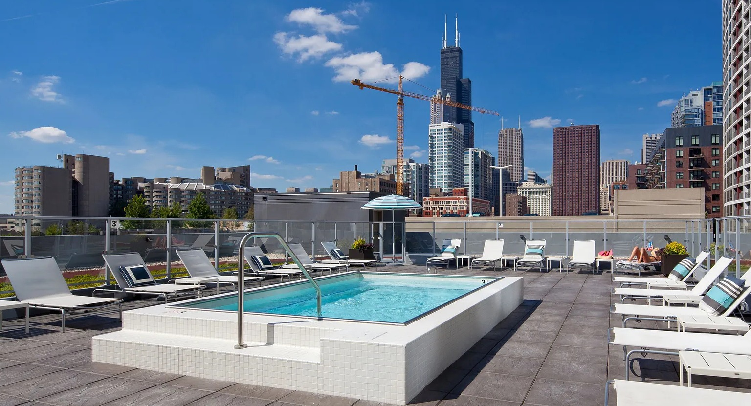 Rooftop spa and sundeck with lounge chairs, glass railings, and skyline views including Willis Tower at 1000 South Clark apartments in Chicago