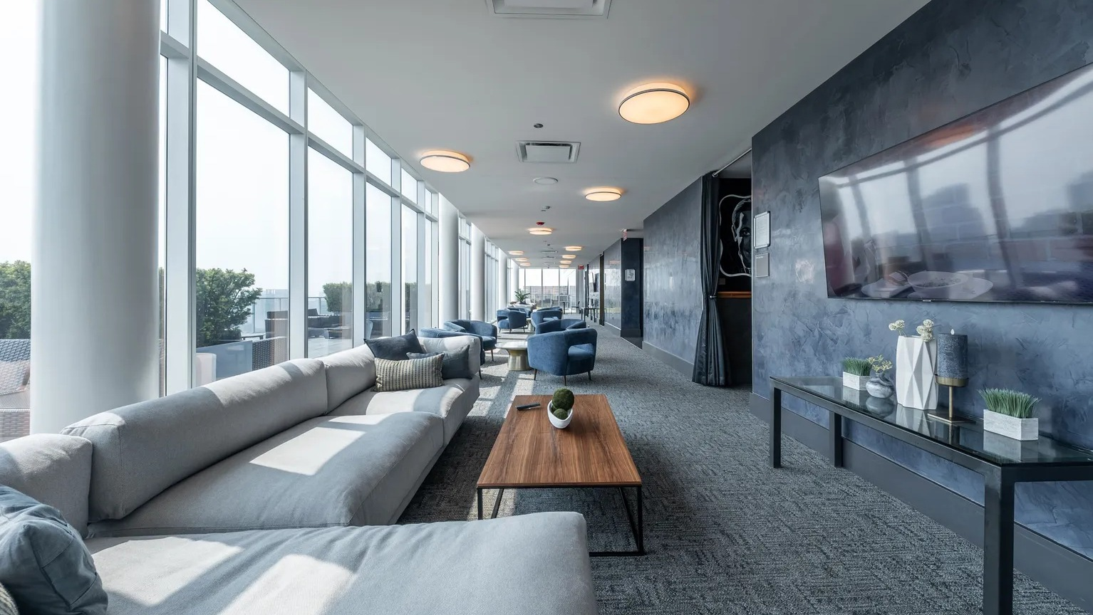 Stylish sky lounge with modern seating, large TV, and floor-to-ceiling windows offering Chicago skyline views at 1000 South Clark apartments