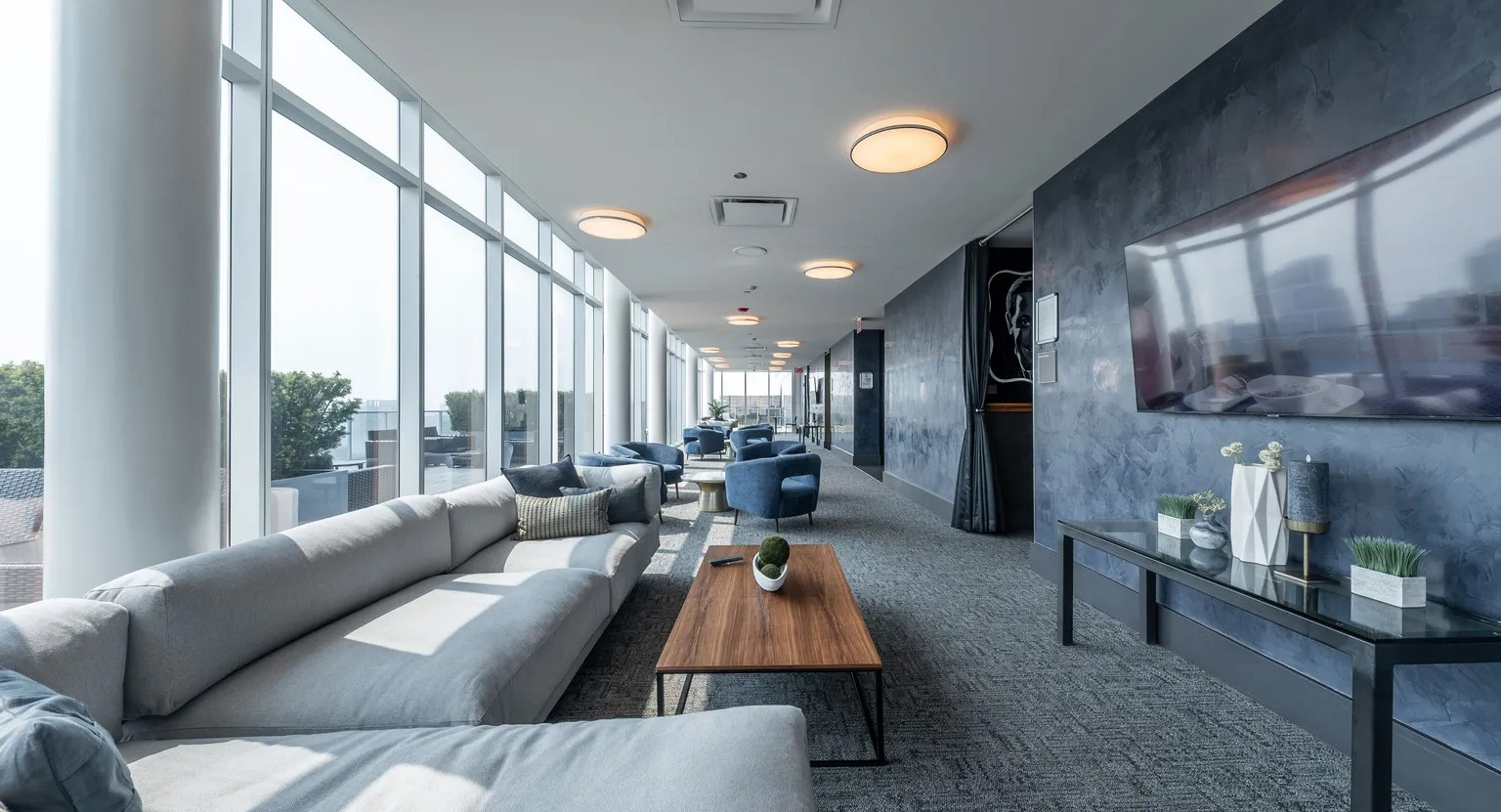 Stylish sky lounge with modern seating, large TV, and floor-to-ceiling windows offering Chicago skyline views at 1000 South Clark apartments