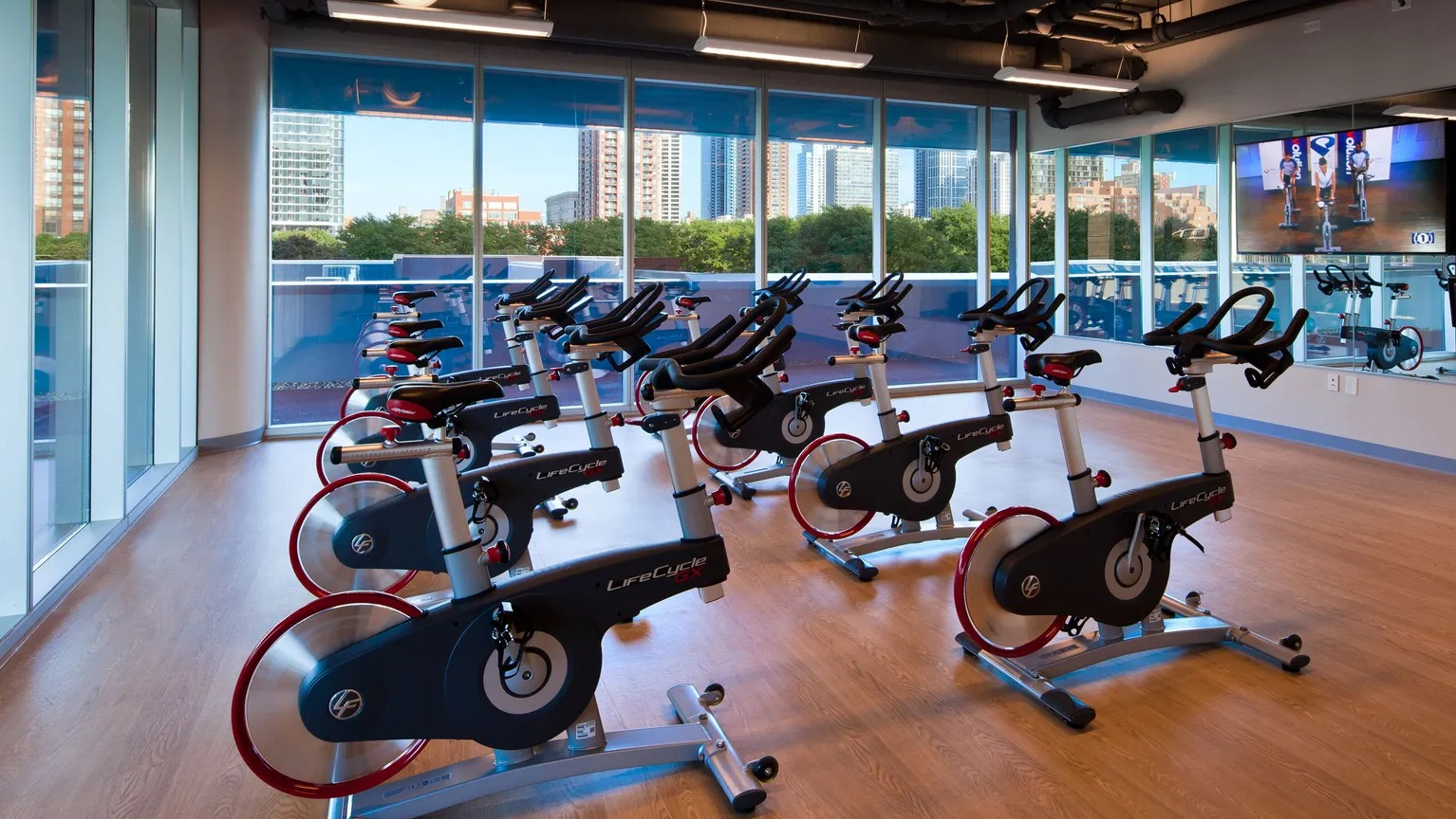 Bright spin studio with rows of stationary bikes and wall-mounted screen at 1000 South Clark apartments in Chicago
