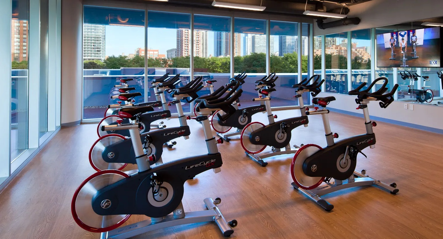 Bright spin studio with rows of stationary bikes and wall-mounted screen at 1000 South Clark apartments in Chicago