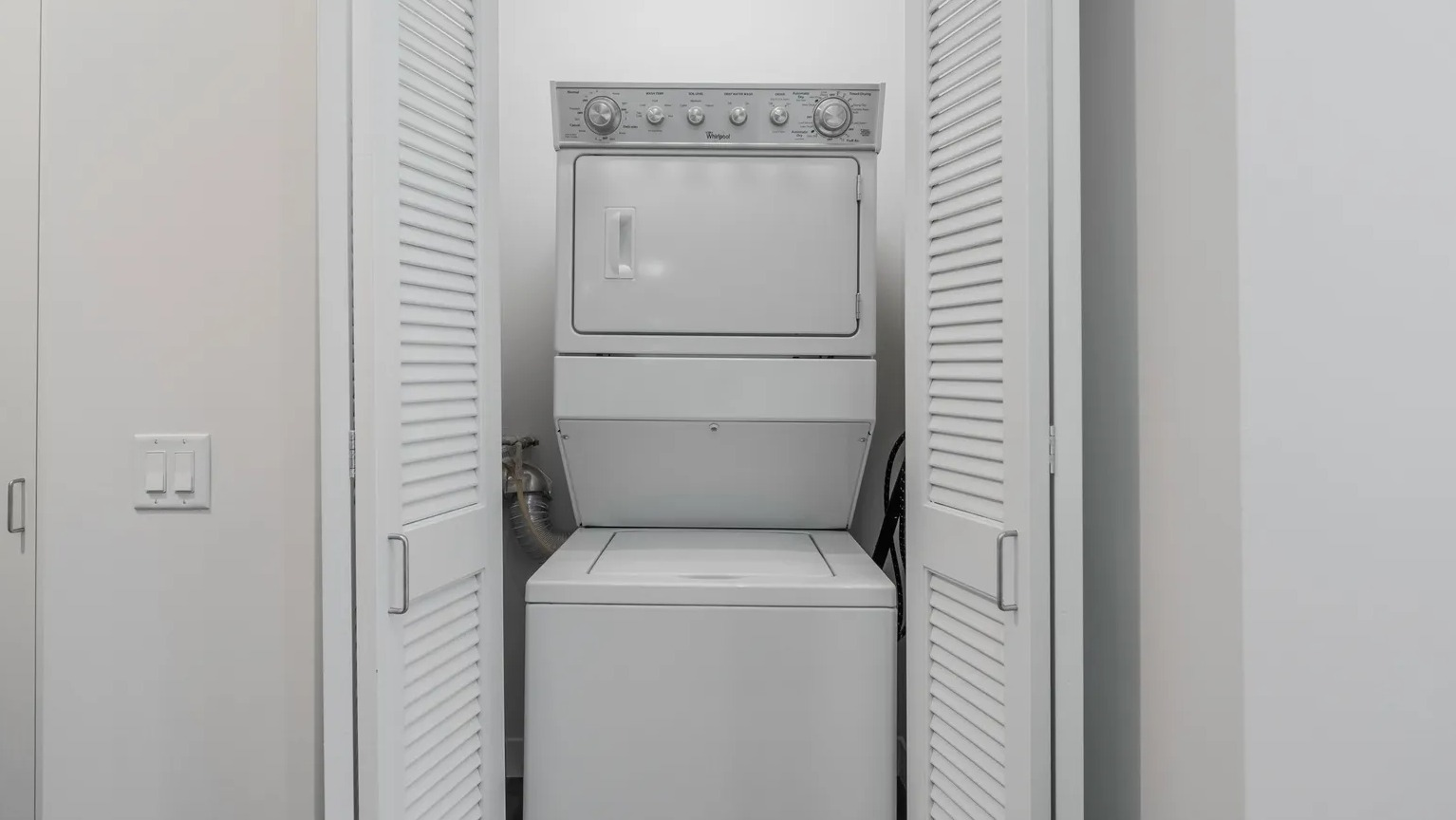 Laundry closet with louvered doors housing stackable washer and dryer, conveniently placed at 1000 South Clark apartments in Chicago