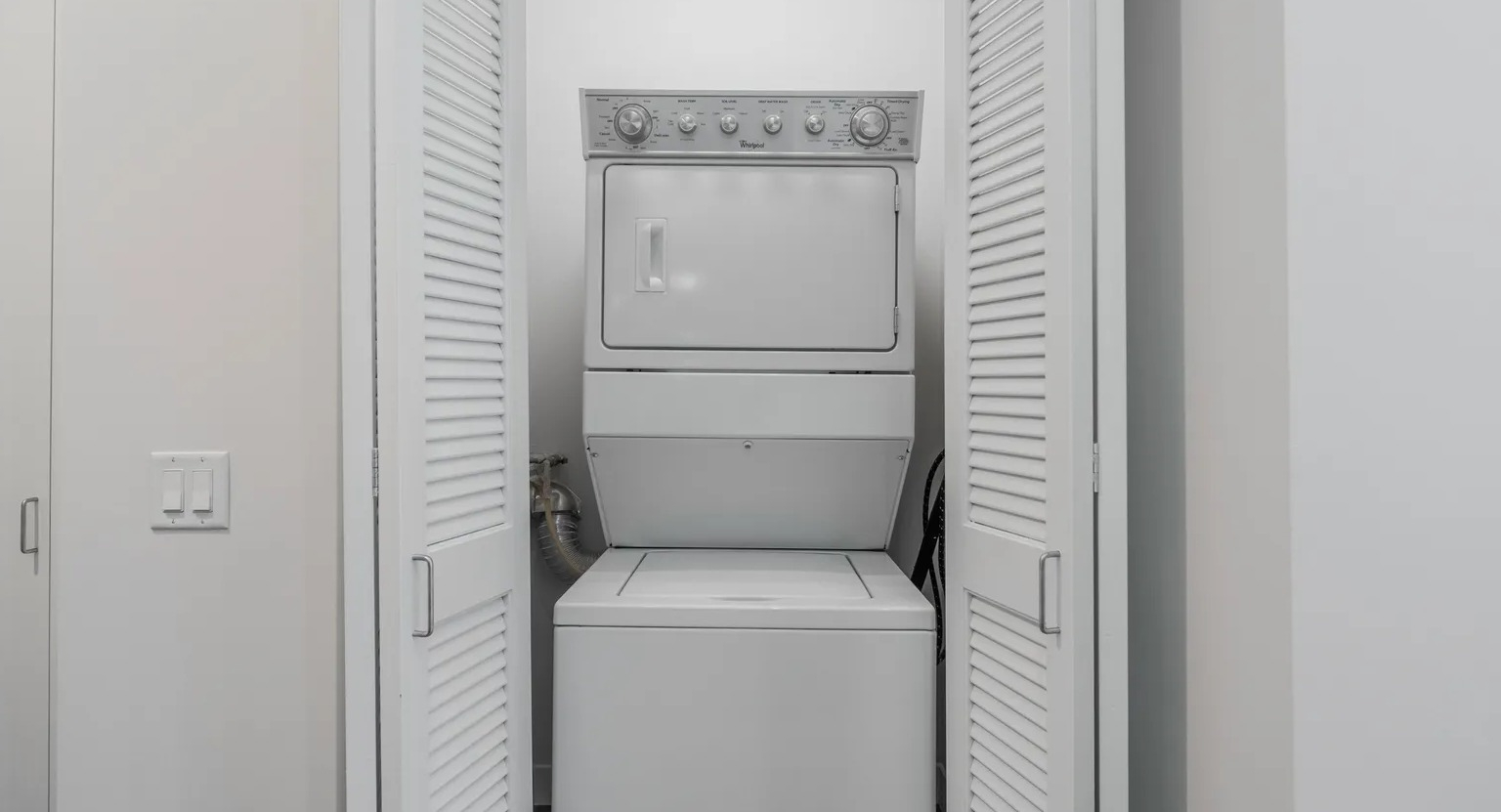 Laundry closet with louvered doors housing stackable washer and dryer, conveniently placed at 1000 South Clark apartments in Chicago