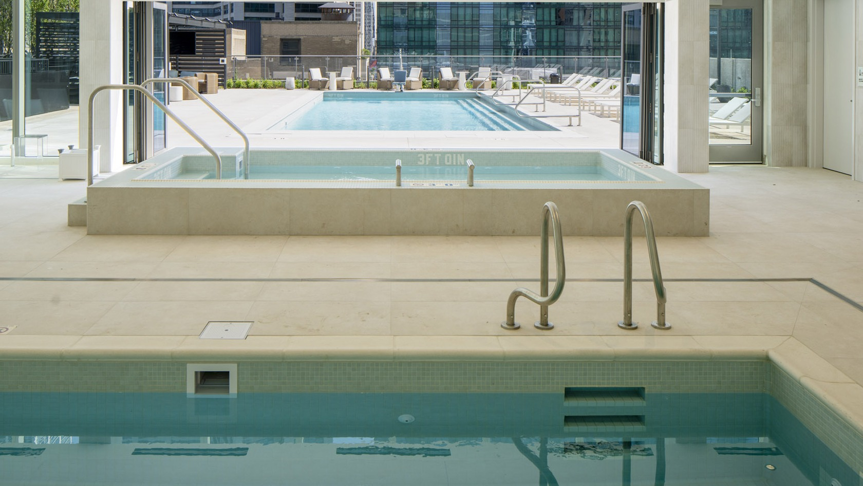 Indoor pool and hot tub seamlessly connected to an outdoor swimming pool with sundeck at 1000M Apartments in Chicago