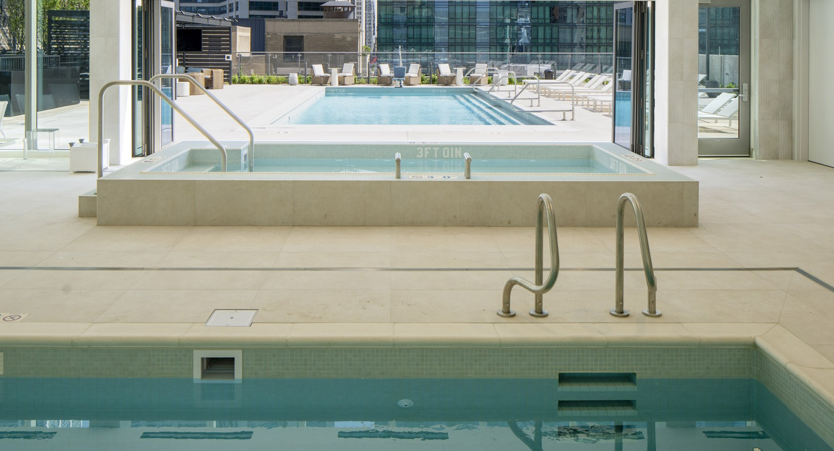 Indoor pool and hot tub seamlessly connected to an outdoor swimming pool with sundeck at 1000M Apartments in Chicago