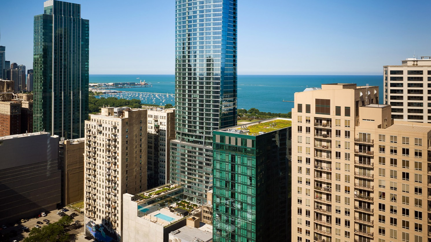 Tall glass residential tower of 1000M Apartments rising above downtown Chicago with views of Lake Michigan in the background