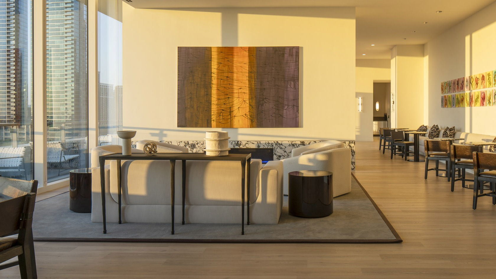 Sun-washed sitting room with contemporary art, café tables, and access to an outdoor terrace overlooking the Chicago skyline at 1000M Apartments