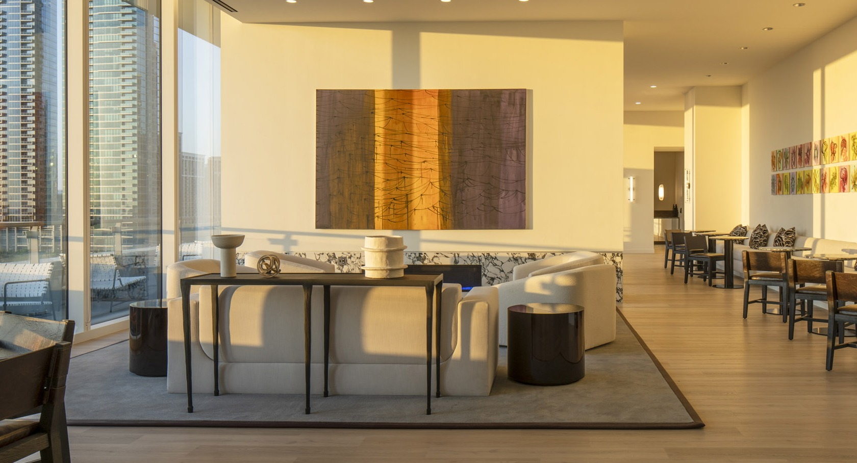 Sun-washed sitting room with contemporary art, café tables, and access to an outdoor terrace overlooking the Chicago skyline at 1000M Apartments