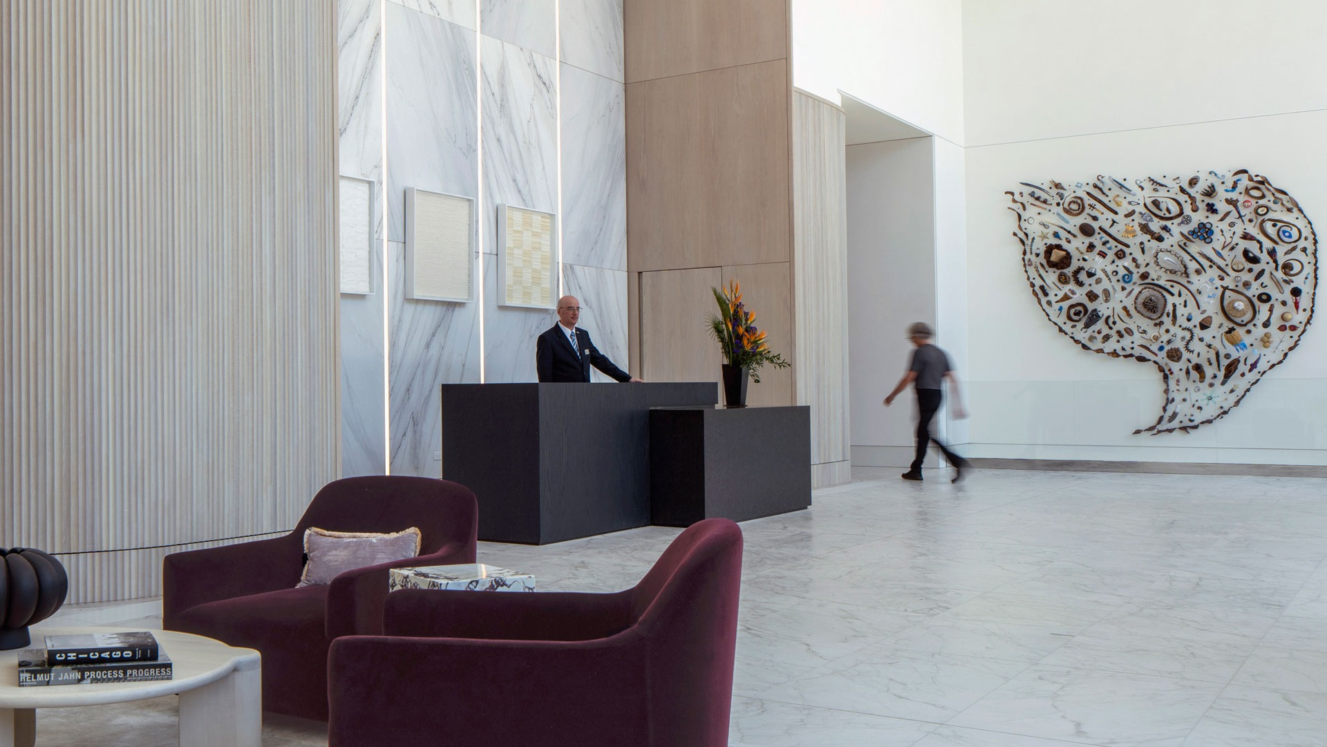 Refined lobby featuring marble finishes, sculptural art, plush seating, and a staffed concierge desk at 1000M Apartments in Chicago