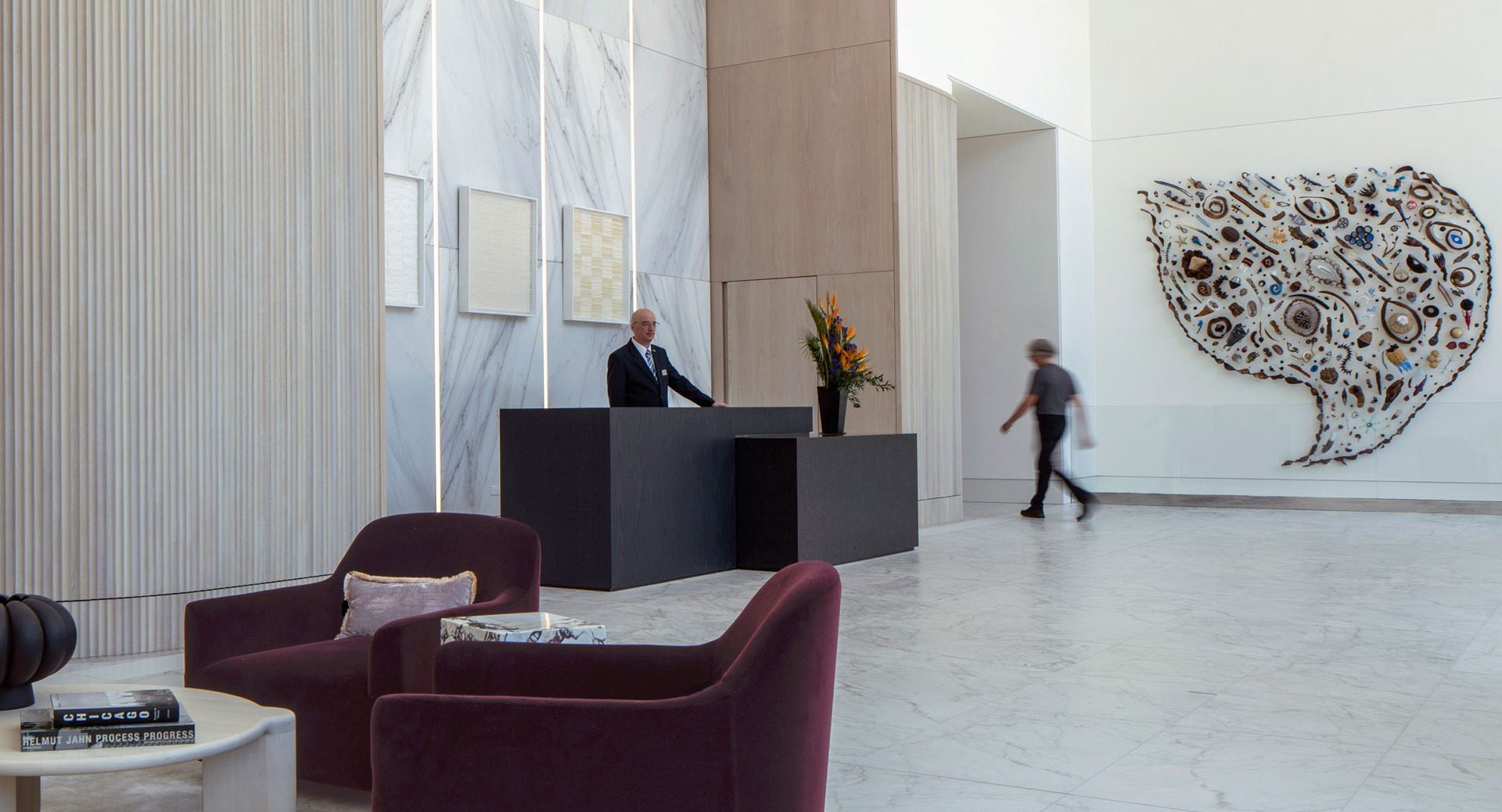 Refined lobby featuring marble finishes, sculptural art, plush seating, and a staffed concierge desk at 1000M Apartments in Chicago