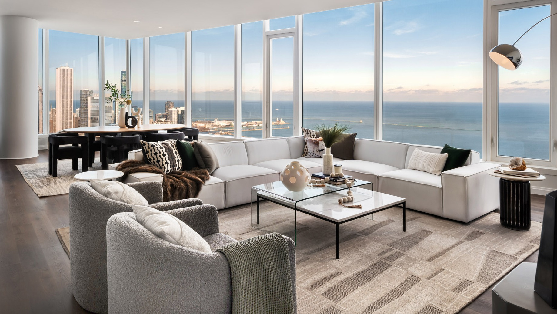 Sophisticated penthouse living room with white sectional, designer décor, and sweeping Lake Michigan and Chicago skyline views at 1000M Apartments